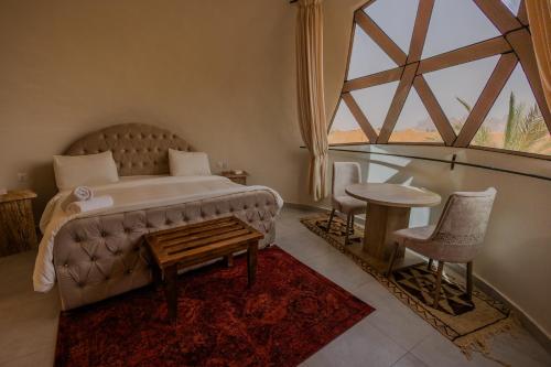 a bedroom with a bed and a table and a window at Bait Ali in Wadi Rum