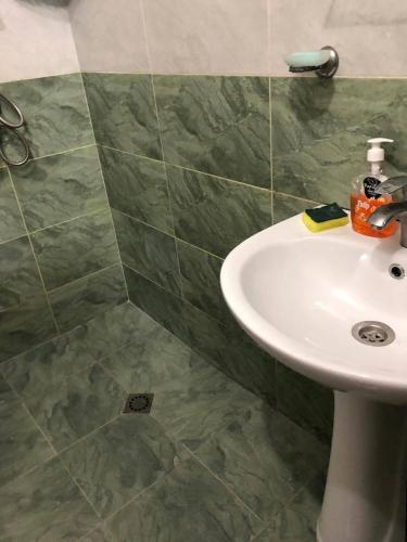 a bathroom with a white sink and green tiles at Квартира in Ureki