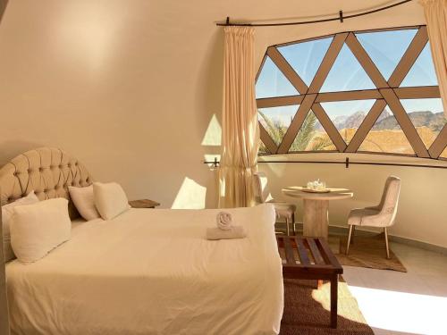 a bedroom with a large bed and a large window at Bait Ali in Wadi Rum
