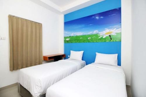 two beds in a room with a painting on the wall at RedDoorz Plus Syariah at Polamas Andalas in Padang
