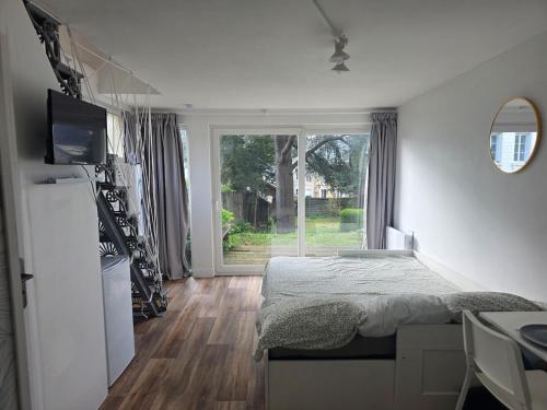 a bedroom with a bed and a large window at Côté Jardin in Bolbec