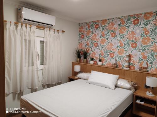 a bedroom with a bed with a floral wallpaper at La Casita de la Suerte 3ro in Marín