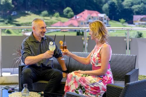 a man and a woman sitting on a patio with drinks at Vital Hotel Krainz mit Nebenhaus Familien Hotel in Loipersdorf bei Fürstenfeld