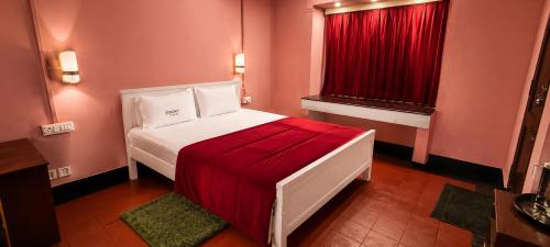 a bedroom with a bed and a red window at Misty D Silver in Munnar