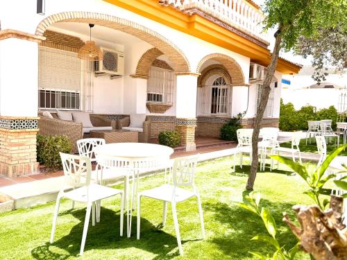 a patio with white tables and chairs in front of a building at Hotel Victoria Matalascañas in Matalascañas