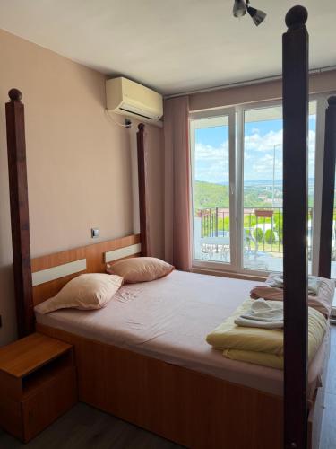 a bedroom with a bed with a large window at Family Hotel Ludo in Varna City