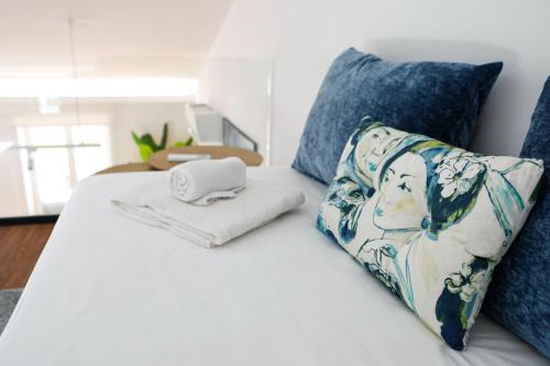 a white bed with a pillow and a towel on it at Décimus Lodge - Premium Town Center Stay in Ponte de Lima