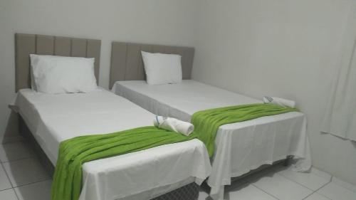 two beds with green blankets on them in a room at Hotel Paulista Sobradinho BA in Sobradinho - Bahia