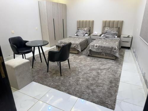 a bedroom with two beds and a table and chairs at راحتي in Al Baha