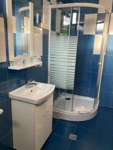 a blue tiled bathroom with a sink and a shower at Casa Poarta Paradisului in Moldoveneşti