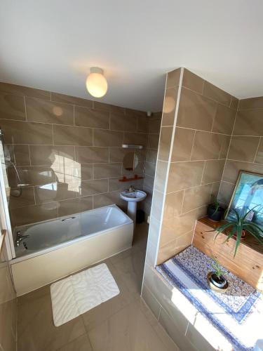 a bathroom with a tub and a toilet and a sink at Atlantic Holiday Home in Milltown Malbay