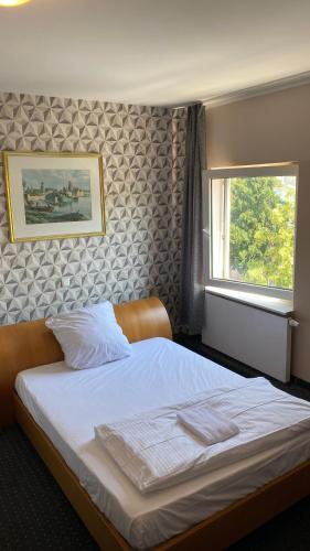 a bedroom with a large white bed with a window at Rosenhof am Main in Offenbach