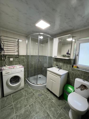a bathroom with a toilet a sink and a washing machine at Затишний дім in Yaremche