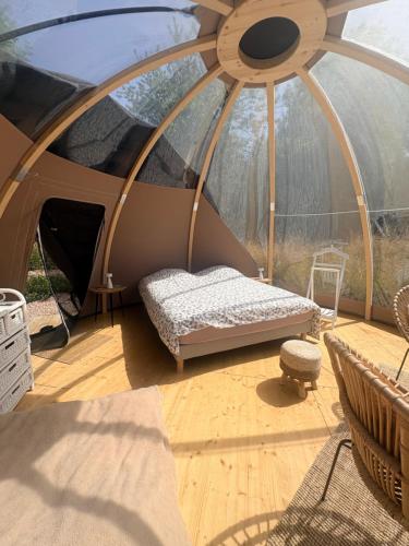 a tent with a bed and a chair in it at La bulle de Clemence in Montfermy