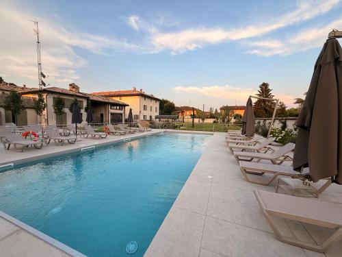 a swimming pool with lounge chairs and umbrellas at Locanda del lupo in Soragna