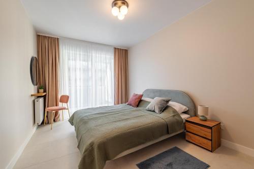 a white bedroom with a bed and a window at Navy Blue Apartment - SPA - Basen - Parking in Dziwnów