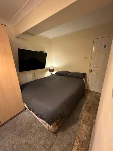 a bedroom with a bed and a flat screen tv at Heathrow Ensuite in West Drayton