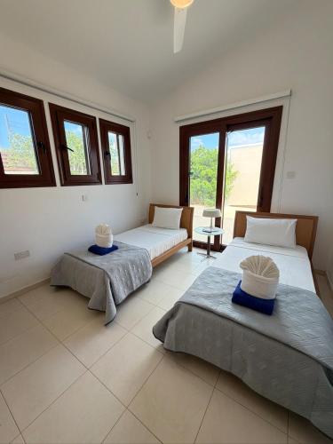 two beds in a room with windows at The Sea Breeze in Paralimni
