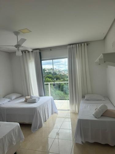 a bedroom with two beds and a large window at Pousada da Esdras in Capitólio