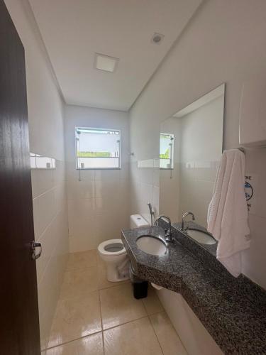 a bathroom with two sinks and a toilet and a mirror at Pousada da Esdras in Capitólio