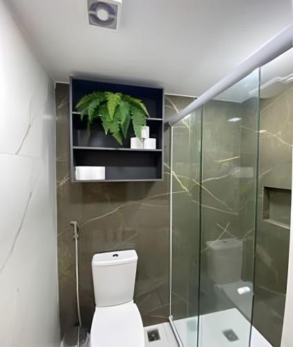 a bathroom with a toilet and a plant on a shelf at Blue Sunset Prime vista do mar e varanda in João Pessoa