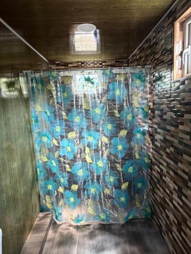a shower curtain with blue flowers on a brick wall at Vefxos Guest home in Anaklia