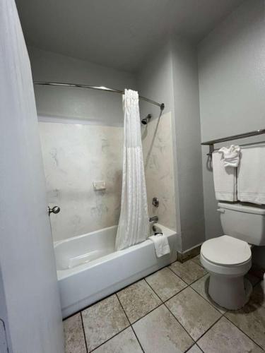 a bathroom with a toilet and a bathtub with a shower curtain at Century Inn in Dallas