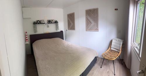 a small bedroom with a bed and a chair at Chalet Feanzicht in Earnewâld