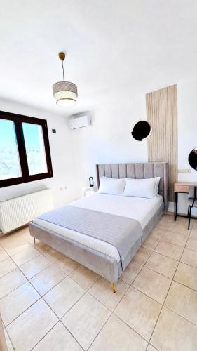 a bedroom with a large bed and two windows at Parea House in Limenaria