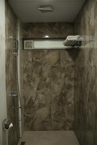 a bathroom with a shower with a stone wall at The Grand Leela Resort in Khopoli