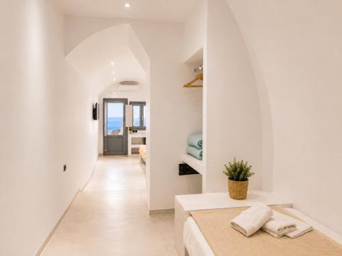 a white room with a bed and a hallway at Cliff Caldera Modern Suites -Volcano, Sunset & Caldera View in Fira