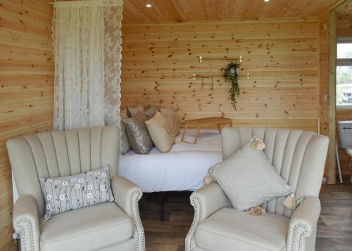 two chairs and a bed in a room with wooden walls at Fine Country Stays in Bubwith