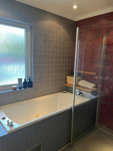 a bath tub in a bathroom with a window at Enplansvilla med pool in Tyresö