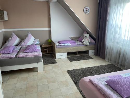 a bedroom with two beds with purple pillows and a teddy bear at Ferienhaus Belkot in Bad Sachsa
