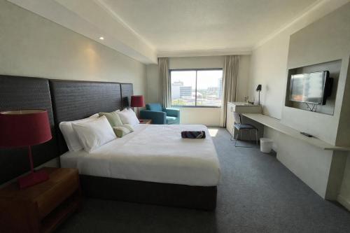 a hotel room with a large bed and a television at Esplanade 88 in Darwin