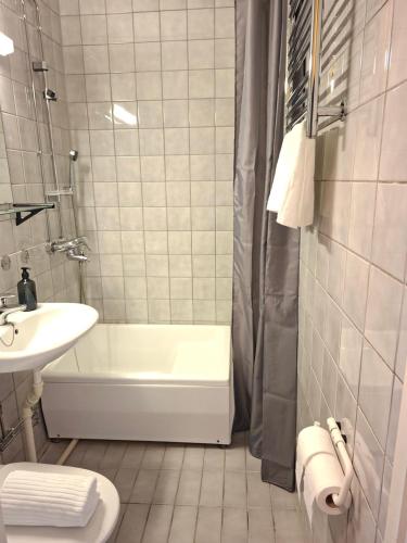 a white bathroom with a tub and a sink at Huone upealla järvimaisemalla in Ikaalinen