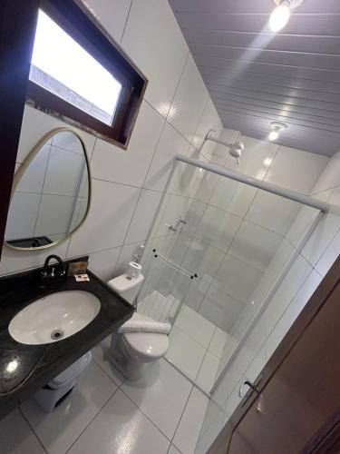 a bathroom with a sink and a toilet and a mirror at Pousada Brisa dos Lençóis in Barreirinhas
