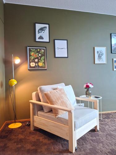 a room with a chair and pictures on the wall at Huone upealla järvimaisemalla in Ikaalinen