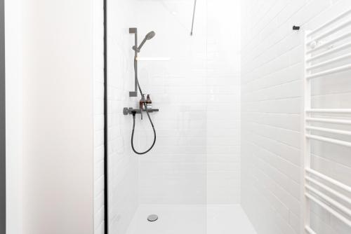 a shower with a shower head in a white bathroom at Global Living Passau Ludwigplatz in Passau