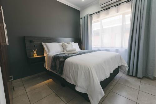a bedroom with a bed with white sheets and a window at Trig Beacon in Manzini