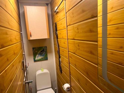 a bathroom with a toilet and wooden walls at Unique and private summer apartment in Tartu