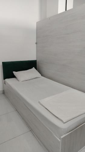 a white bed in a room with a green headboard at Em capsule Hostel Baku in Baku