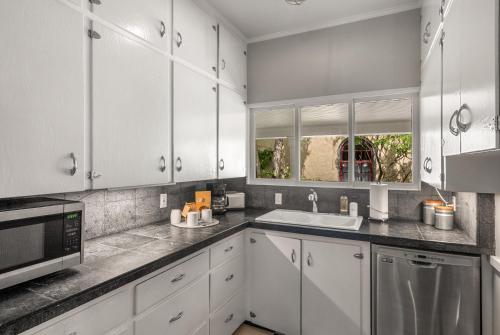 a kitchen with white cabinets and a sink and a microwave at 7th Street Bungalow in Livingston