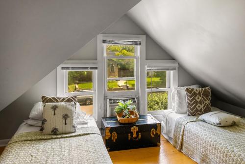 a attic room with two beds and two windows at 7th Street Bungalow in Livingston