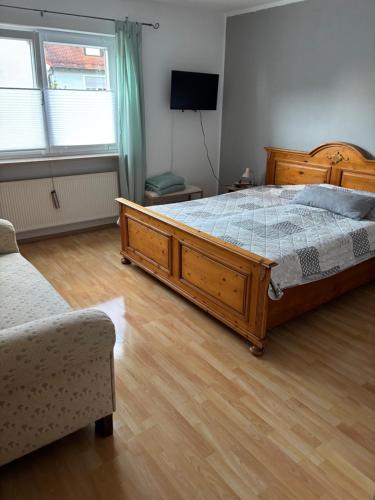 a bedroom with a wooden bed and a couch at Ferienwohnung Aurach in Aurach
