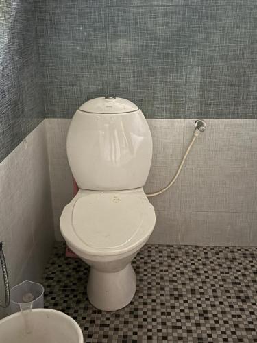 a white toilet in a bathroom with a hose at The Brick Nest in Perumpāvūr