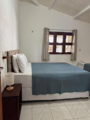 a bedroom with a bed with a blue blanket and a window at Casa Paraíso Guajiru in Trairi