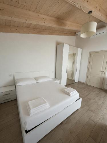 a white bedroom with a large white bed and wooden ceilings at Casa vacanze indipendente in Follonica