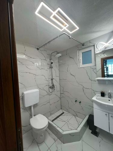 a white bathroom with a toilet and a sink at Apartman Kastel in Travnik