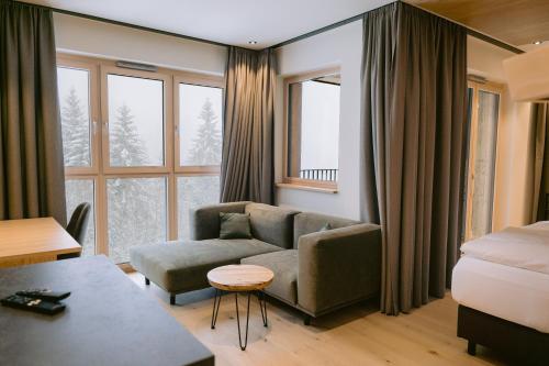 a living room with a couch and a bed at Das Waldhotel - Spa & Wellness Resort in Todtnau